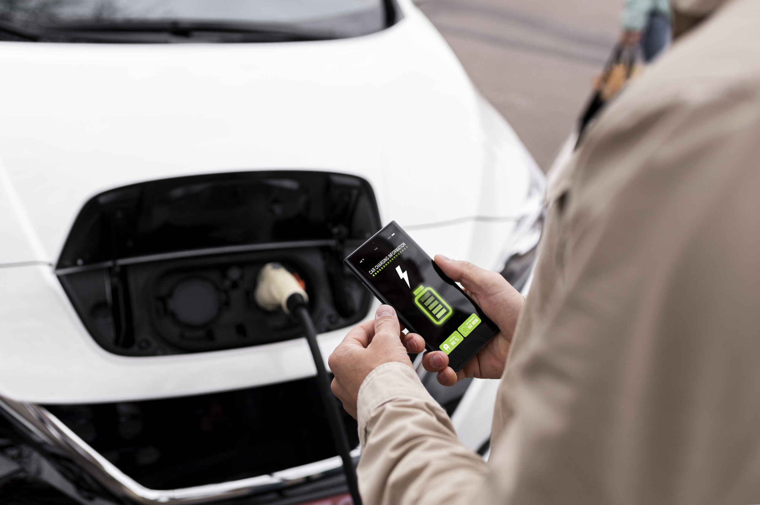 Persoon laadt elektrische auto op en ziet batterij op telefoon.